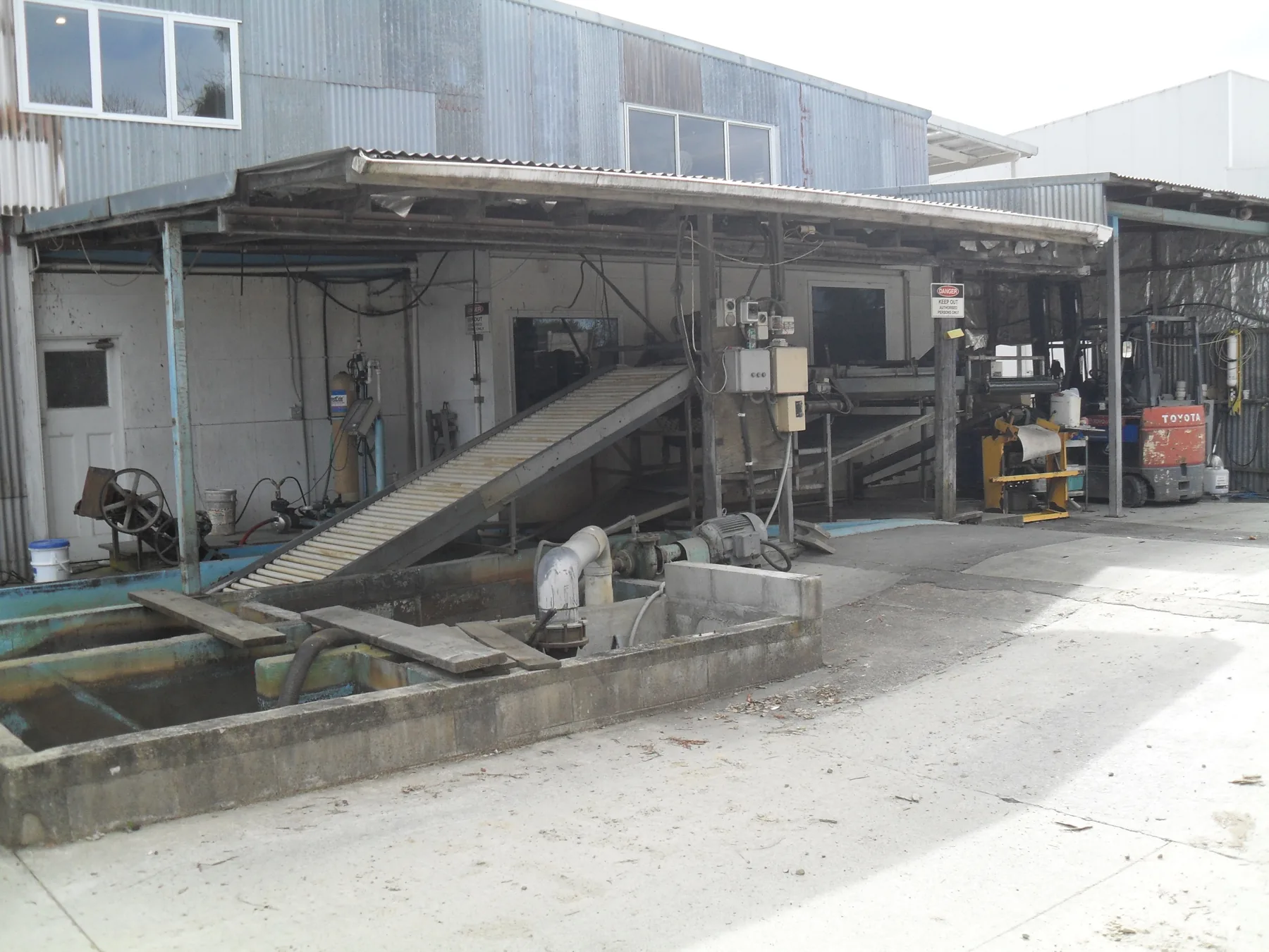 Outdoor waterbath infeed and conveyor arrangement at an orchard processing facility