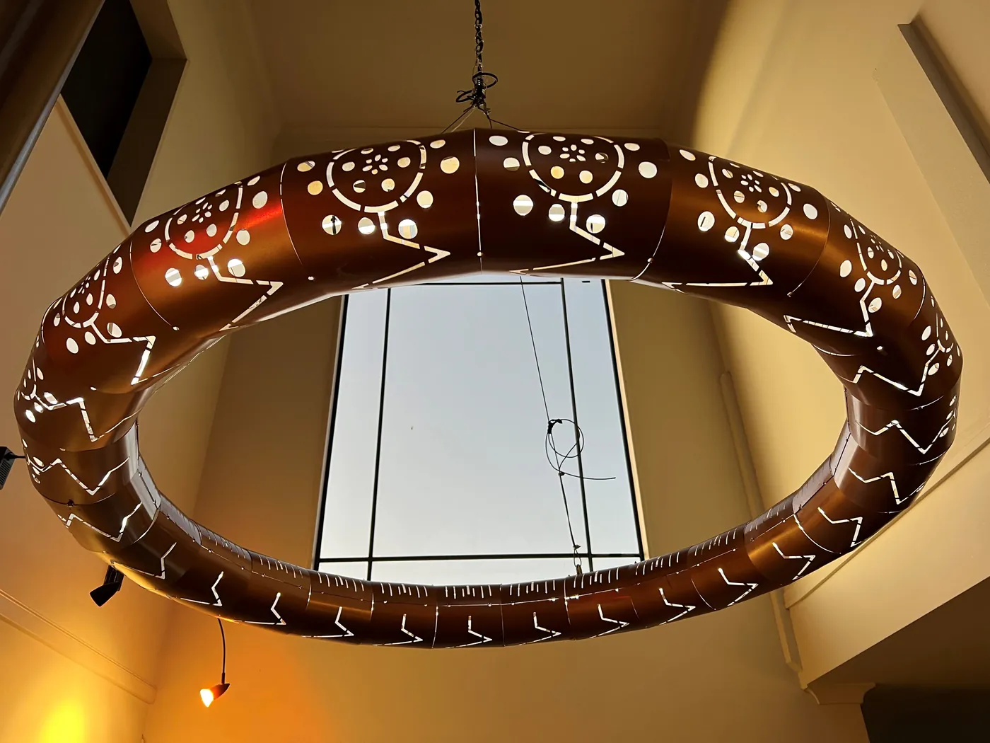 Copper-toned custom ring light with laser-cut patterning and warm backlighting.