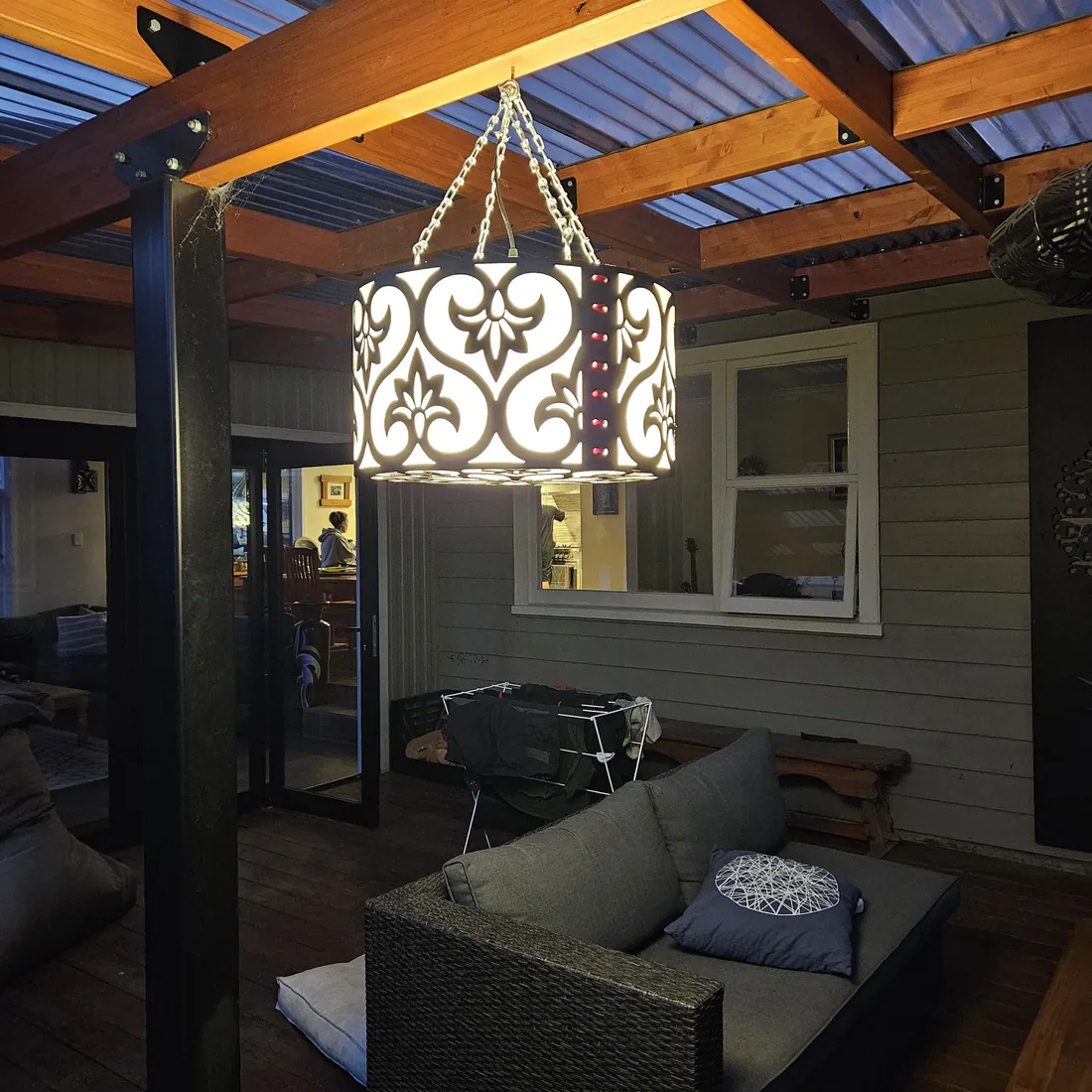 Installed patterned pendant light glowing beneath a timber canopy